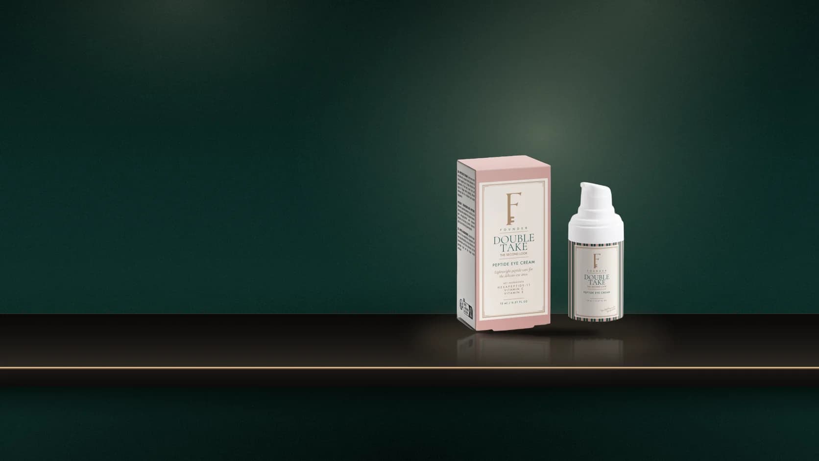 The Double Take bottle and carton on a marble dressing table with a pearl applicator, a gilt mirror and bulb light behind.